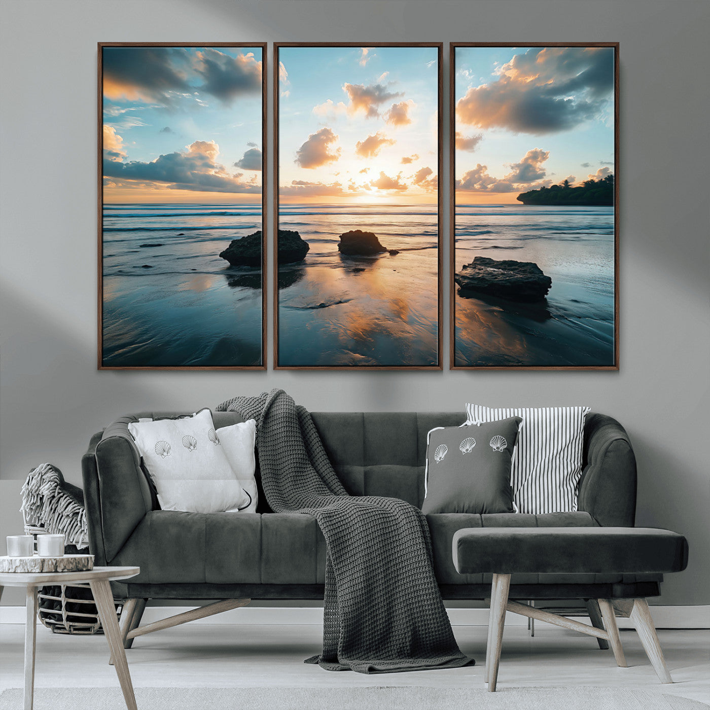 A serene beach at sunset with vibrant clouds, calm water, and rocks in the foreground reflecting the warm colors of the setting sun.