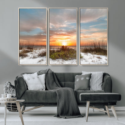 A tranquil beach scene featuring golden sunset hues over the water, with grasses in the foreground and a peaceful, serene atmosphere.