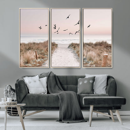 A peaceful coastal pathway leading to the ocean, with birds flying across a soft pastel sky, creating a calm and scenic beach atmosphere.
