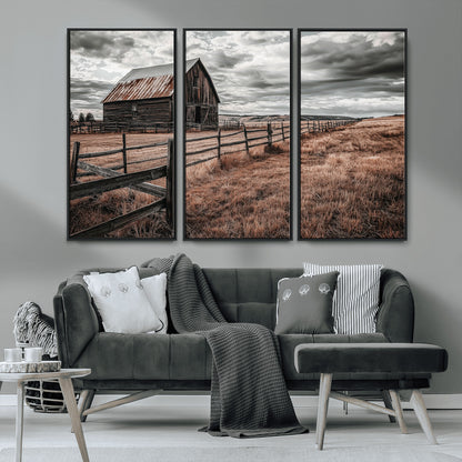 Framed canvas of a rustic barn under a moody sky with weathered fence and dark fields, ideal for farmhouse or rural-style wall decor.
