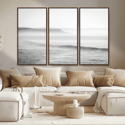 A black and white minimalist seascape featuring soft rolling waves and misty distant cliffs, creating a serene and timeless coastal atmosphere.