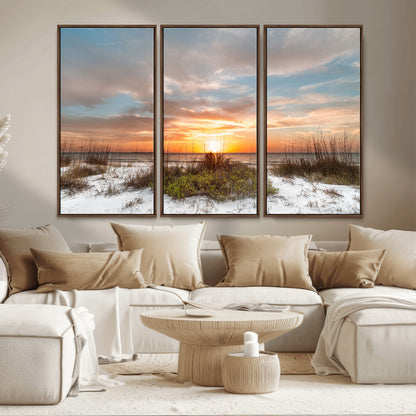 A tranquil beach scene featuring golden sunset hues over the water, with grasses in the foreground and a peaceful, serene atmosphere.