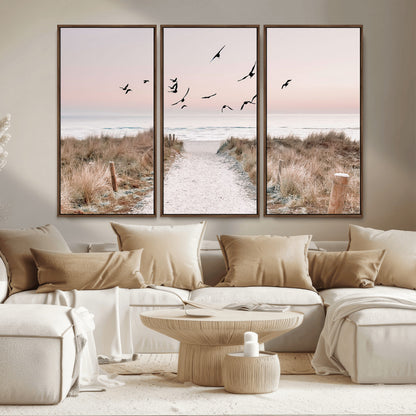 A peaceful coastal pathway leading to the ocean, with birds flying across a soft pastel sky, creating a calm and scenic beach atmosphere.