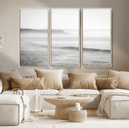 A black and white minimalist seascape featuring soft rolling waves and misty distant cliffs, creating a serene and timeless coastal atmosphere.