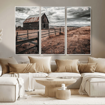 Framed canvas of a rustic barn under a moody sky with weathered fence and dark fields, ideal for farmhouse or rural-style wall decor.