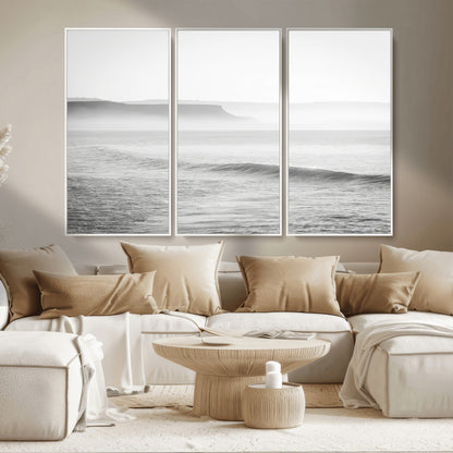 A black and white minimalist seascape featuring soft rolling waves and misty distant cliffs, creating a serene and timeless coastal atmosphere.