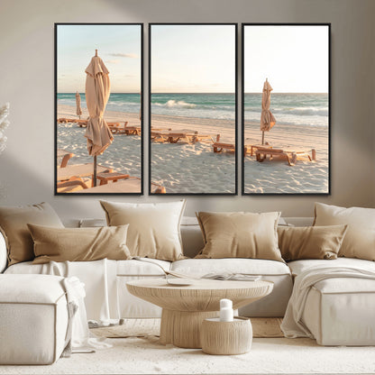 Minimalist photo of empty beach loungers and umbrellas on soft sand, ideal for calm seaside or pastel coastal-style home decor.