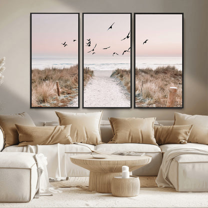 A peaceful coastal pathway leading to the ocean, with birds flying across a soft pastel sky, creating a calm and scenic beach atmosphere.