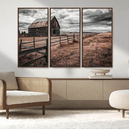 Framed canvas of a rustic barn under a moody sky with weathered fence and dark fields, ideal for farmhouse or rural-style wall decor.