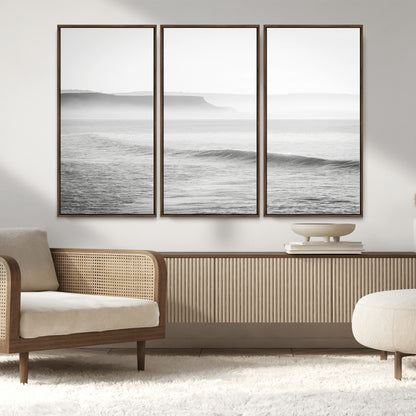 A black and white minimalist seascape featuring soft rolling waves and misty distant cliffs, creating a serene and timeless coastal atmosphere.