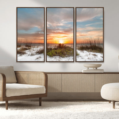 A tranquil beach scene featuring golden sunset hues over the water, with grasses in the foreground and a peaceful, serene atmosphere.