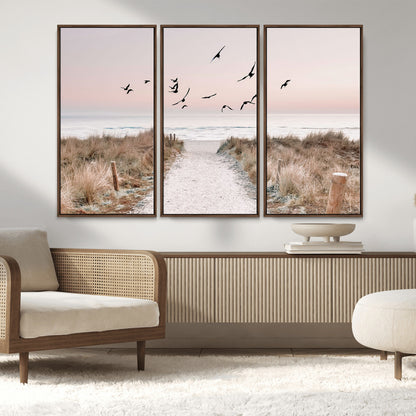 A peaceful coastal pathway leading to the ocean, with birds flying across a soft pastel sky, creating a calm and scenic beach atmosphere.