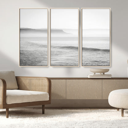 A black and white minimalist seascape featuring soft rolling waves and misty distant cliffs, creating a serene and timeless coastal atmosphere.