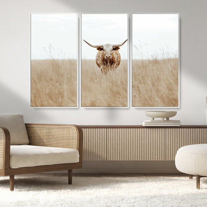 Texas Longhorn bull standing alone in dry grass with neutral tones, ideal for rustic western or cowboy-themed wall decor.
