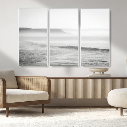 A black and white minimalist seascape featuring soft rolling waves and misty distant cliffs, creating a serene and timeless coastal atmosphere.