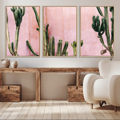 Framed canvas of tall green cacti against a soft pink wall, ideal for modern desert or colorful southwest-inspired home decor.