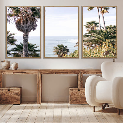 Scenic coastal view with tall palm trees overlooking a calm ocean, soft blue waves, and surfers in the distance, creating a peaceful tropical vibe.