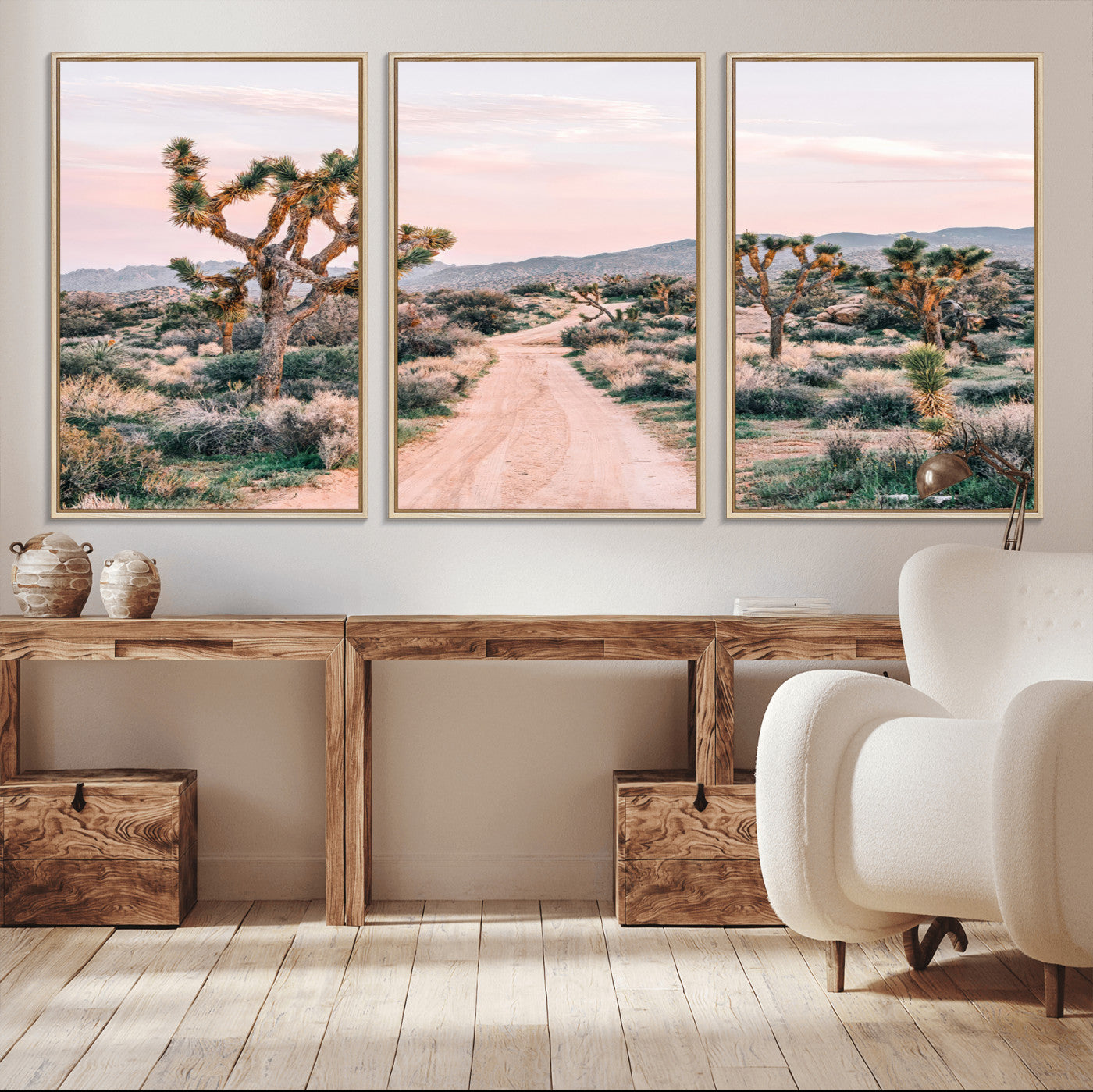 A dusty road winding through Joshua Tree National Park, framed by iconic twisted trees and warm desert tones under a soft pastel sky.