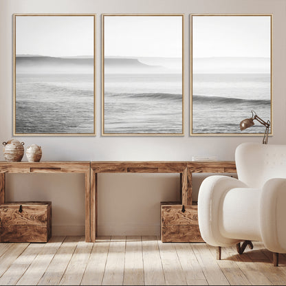 A black and white minimalist seascape featuring soft rolling waves and misty distant cliffs, creating a serene and timeless coastal atmosphere.