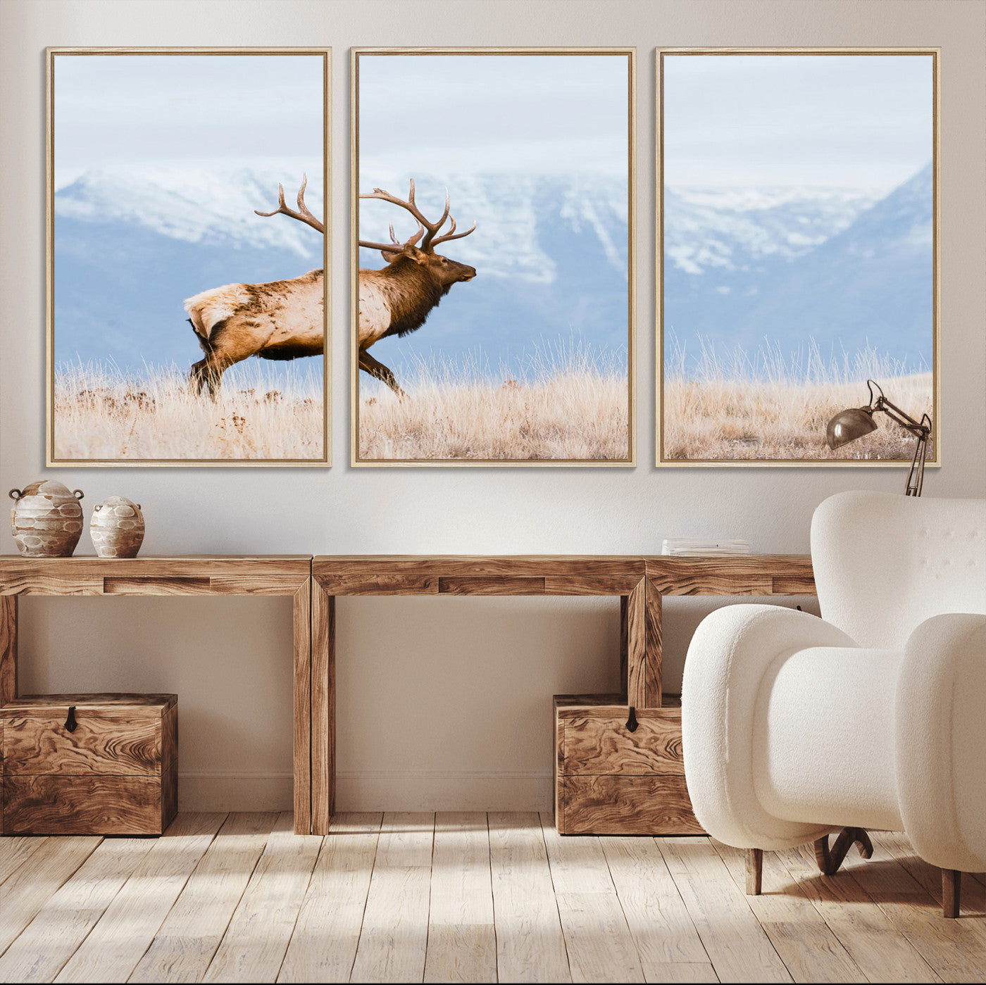 An elk walking on snowy grassland with majestic mountains in the background, ideal for rustic lodge or cabin wall decor.