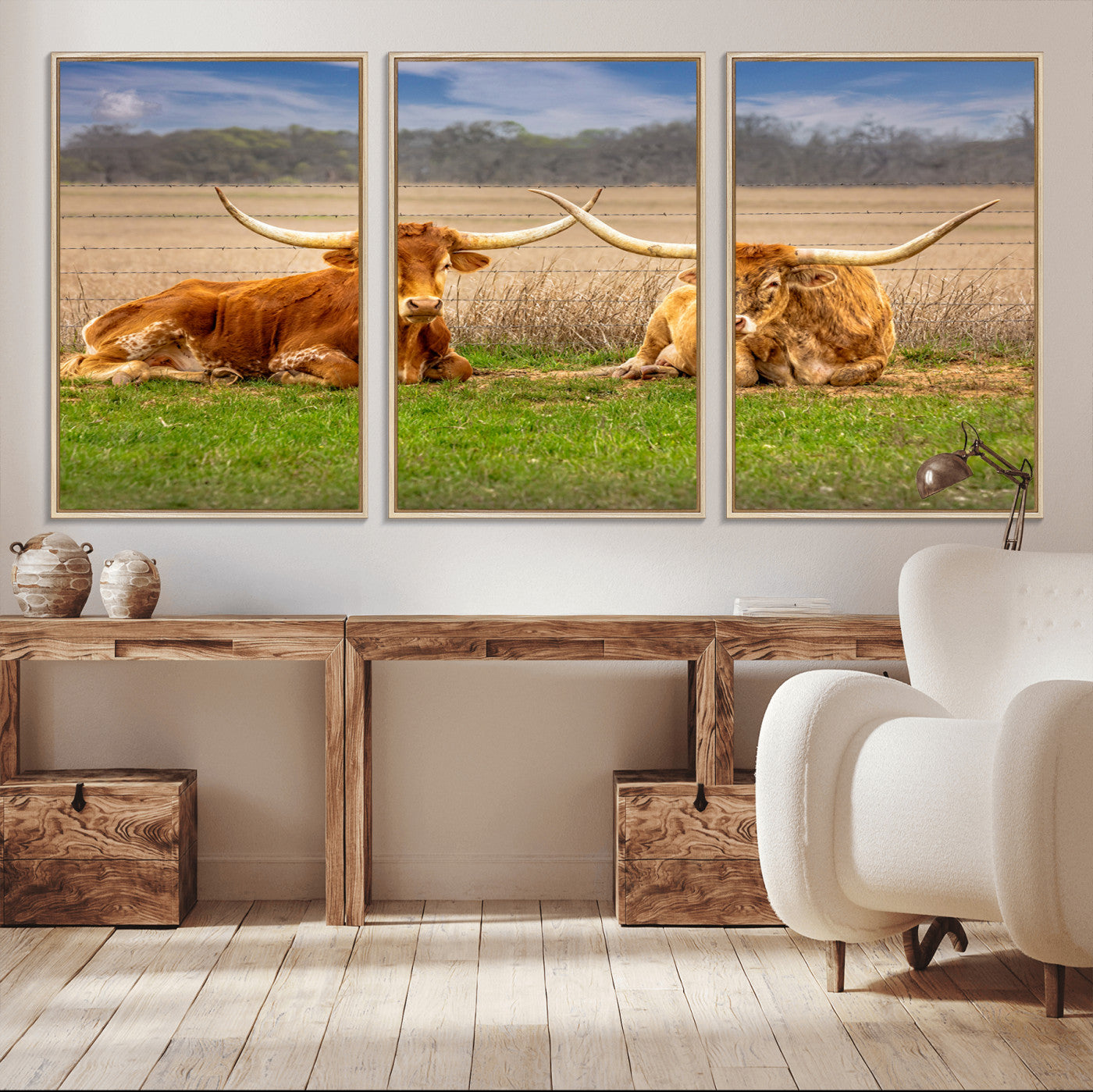 Two longhorn cows lying on green grass in front of a golden field and trees under a blue sky, perfect for rustic country wall decor.
