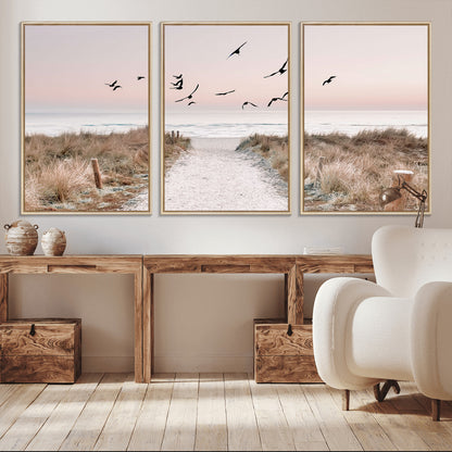 A peaceful coastal pathway leading to the ocean, with birds flying across a soft pastel sky, creating a calm and scenic beach atmosphere.