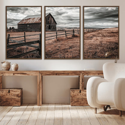 Framed canvas of a rustic barn under a moody sky with weathered fence and dark fields, ideal for farmhouse or rural-style wall decor.