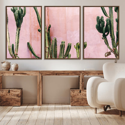 Framed canvas of tall green cacti against a soft pink wall, ideal for modern desert or colorful southwest-inspired home decor.