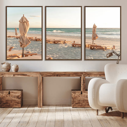 Minimalist photo of empty beach loungers and umbrellas on soft sand, ideal for calm seaside or pastel coastal-style home decor.
