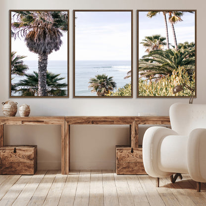 Scenic coastal view with tall palm trees overlooking a calm ocean, soft blue waves, and surfers in the distance, creating a peaceful tropical vibe.