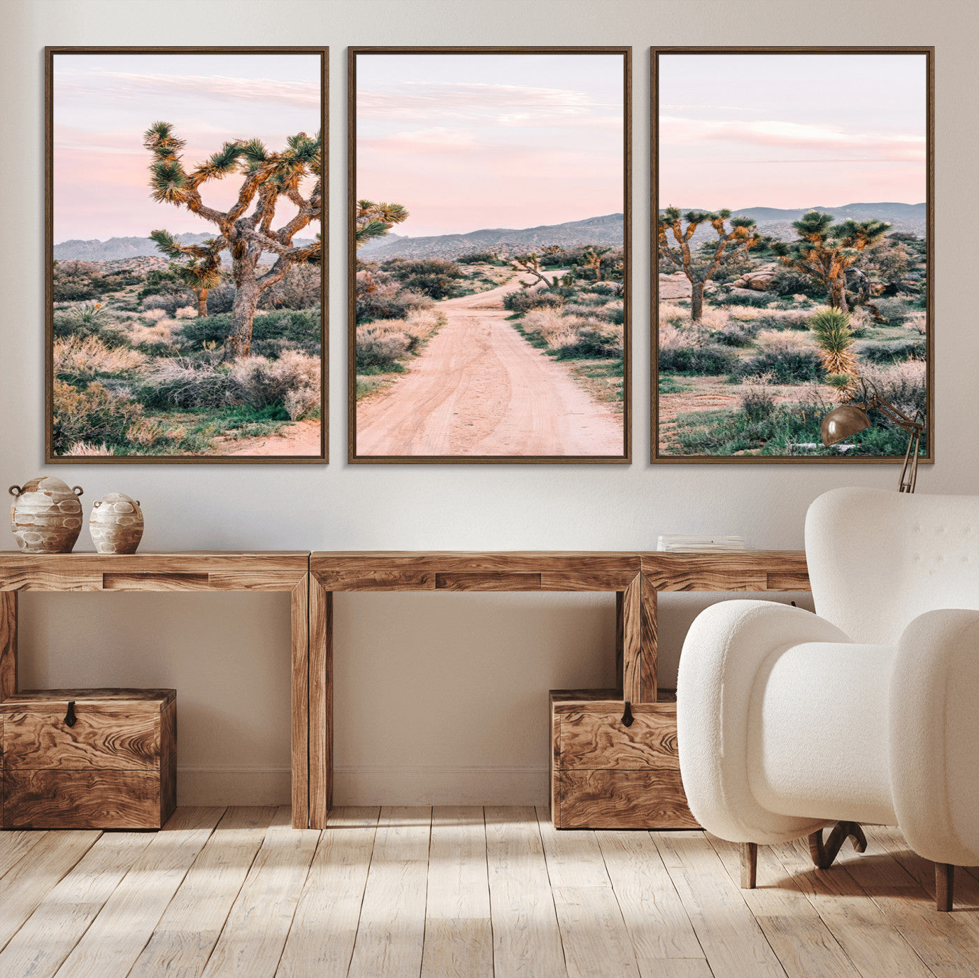 A dusty road winding through Joshua Tree National Park, framed by iconic twisted trees and warm desert tones under a soft pastel sky.