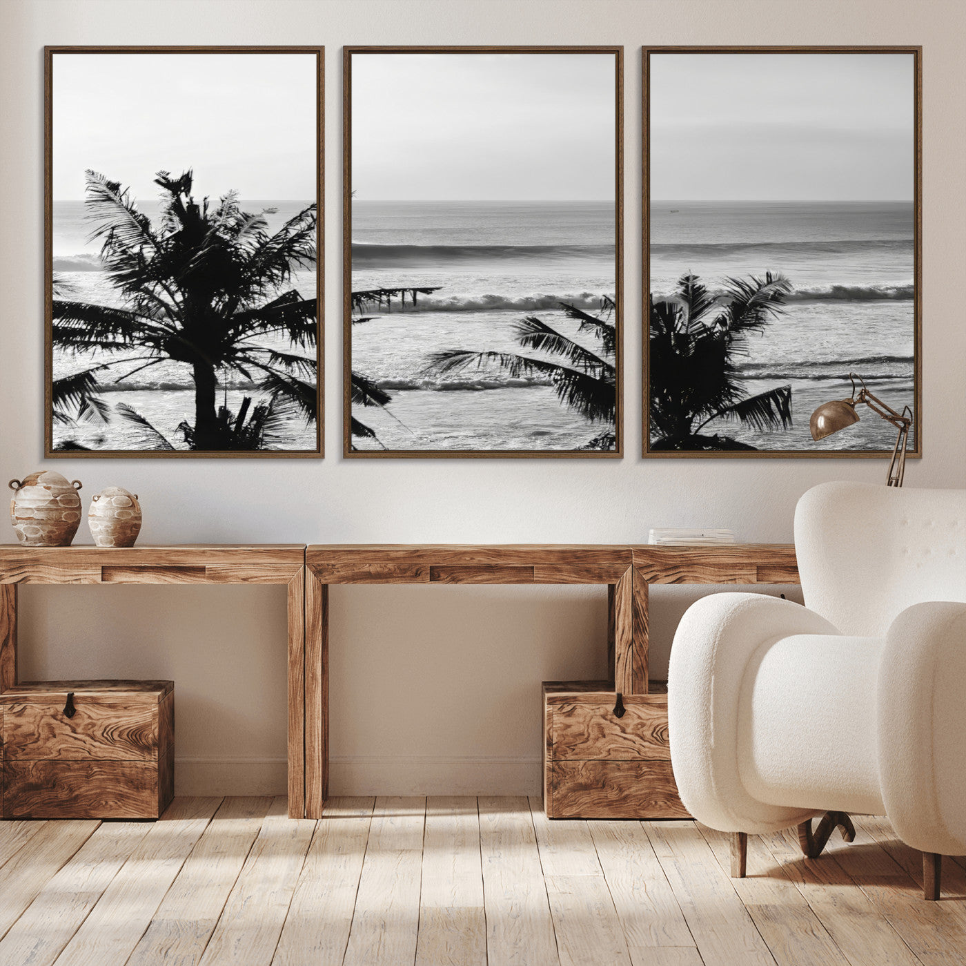 Black and white view of ocean waves crashing on a tropical coastline, framed by silhouetted palm trees under a vast, open sky.