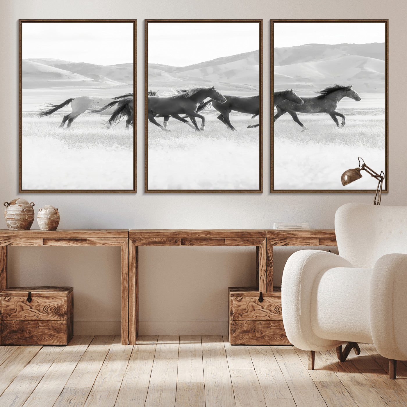 A black and white image of wild horses running freely across an open grassland, capturing the power and beauty of untamed nature in a rustic western setting.