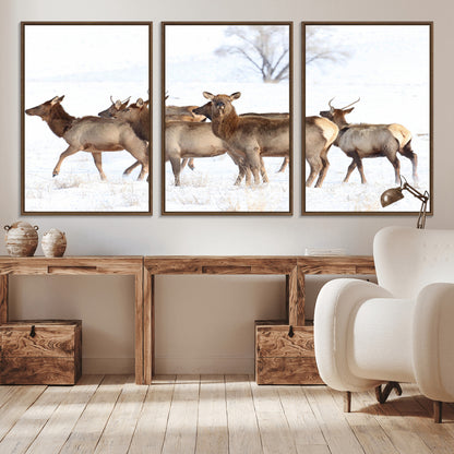 A group of elk standing on snowy terrain with a tree in the background, perfect for rustic or lodge-style winter wall decor.