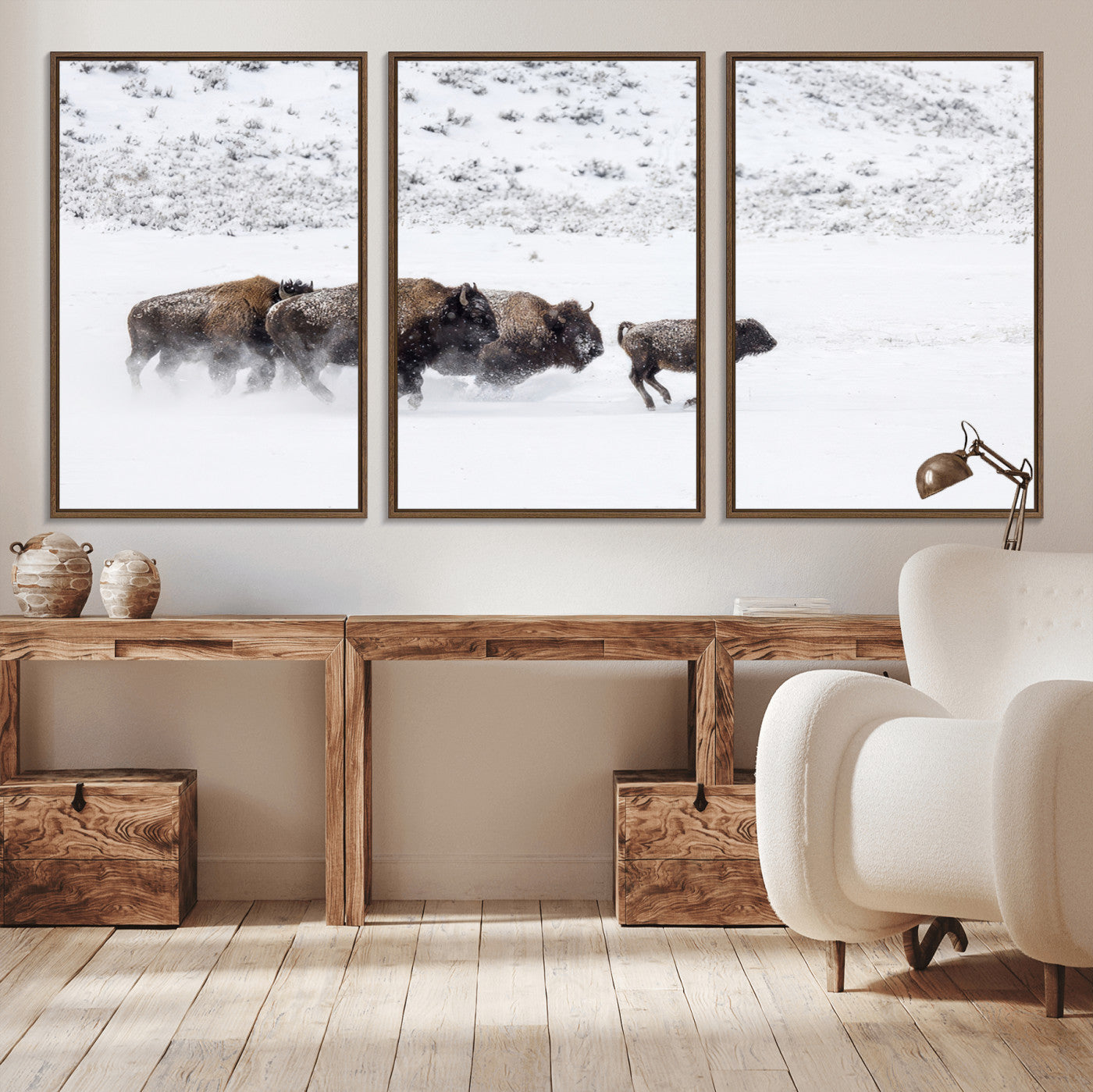 Bison herd running through a snowy open field with mountain backdrop, perfect for rustic or western-themed wall decoration.