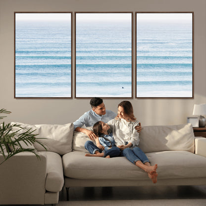 Minimalist ocean view with soft blue waves and a lone surfer, creating a serene and airy coastal aesthetic, perfect for tranquil home decor.