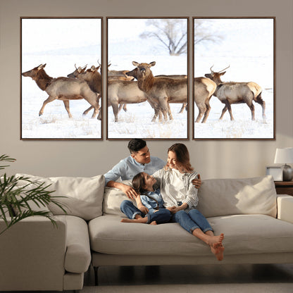 A group of elk standing on snowy terrain with a tree in the background, perfect for rustic or lodge-style winter wall decor.