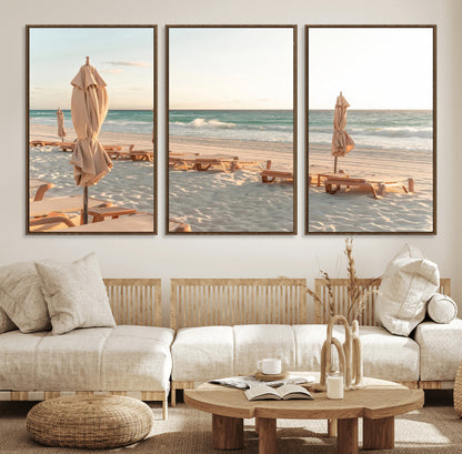 Minimalist photo of empty beach loungers and umbrellas on soft sand, ideal for calm seaside or pastel coastal-style home decor.
