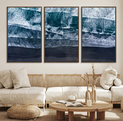 Canvas of aerial ocean waves crashing onto a black sand beach in moody tones, ideal for modern coastal or minimalist home decor.