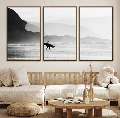 A lone surfer walking along a misty beach with cliffs in the background, carrying their board, capturing a serene and minimal ocean moment.