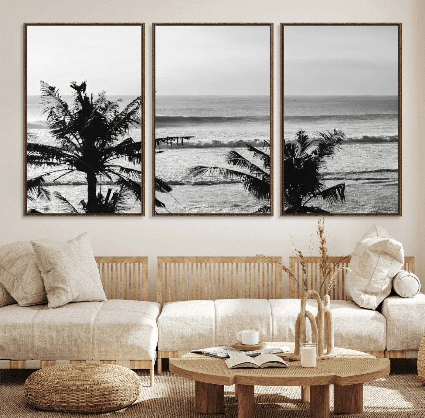 Black and white view of ocean waves crashing on a tropical coastline, framed by silhouetted palm trees under a vast, open sky.
