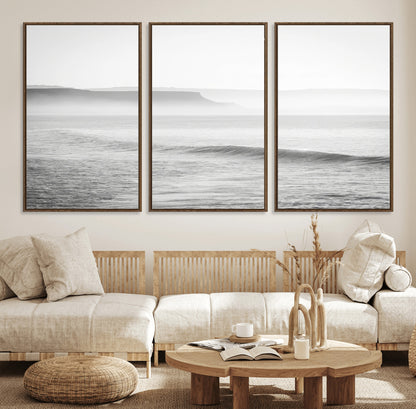 A black and white minimalist seascape featuring soft rolling waves and misty distant cliffs, creating a serene and timeless coastal atmosphere.