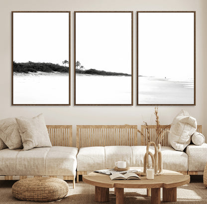 A black and white minimalist coastal scene with a vast open beach, distant palm trees, and a lone figure walking along the shoreline, evoking serenity and solitude.