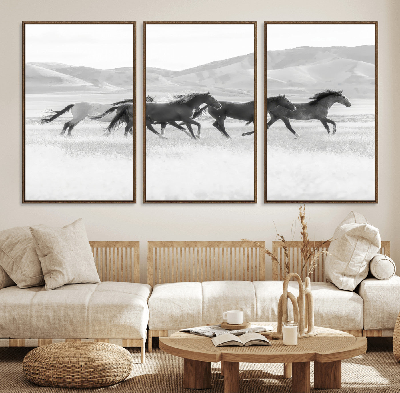A black and white image of wild horses running freely across an open grassland, capturing the power and beauty of untamed nature in a rustic western setting.