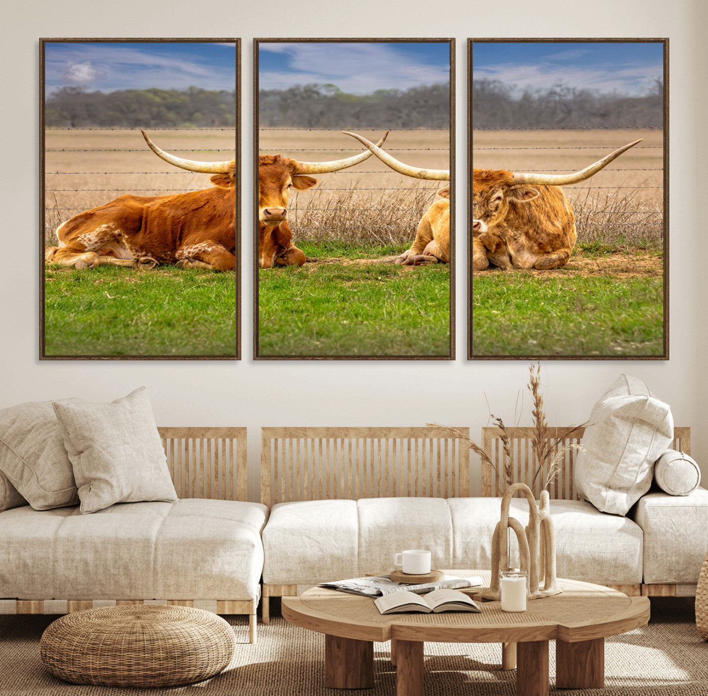 Two longhorn cows lying on green grass in front of a golden field and trees under a blue sky, perfect for rustic country wall decor.