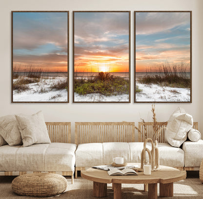 A tranquil beach scene featuring golden sunset hues over the water, with grasses in the foreground and a peaceful, serene atmosphere.