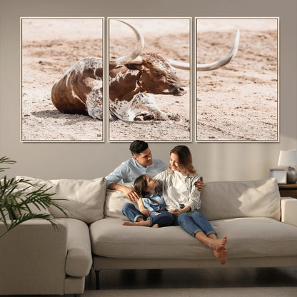 Texas Longhorn bull resting on dusty ground with warm tones, ideal for rustic western or farmhouse-themed wall decor.