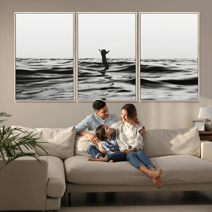 Black and white ocean with a hand making a surfer sign among dark waves, creating a dramatic and minimalist seascape with bold contrast.