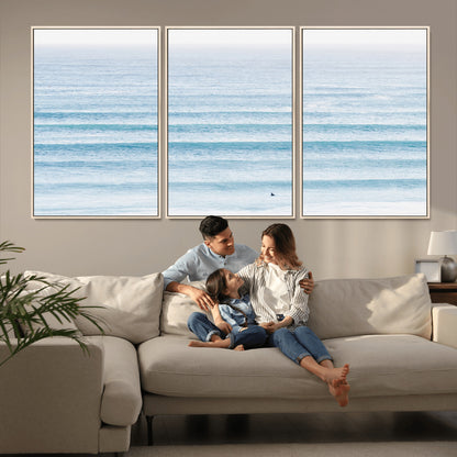 Minimalist ocean view with soft blue waves and a lone surfer, creating a serene and airy coastal aesthetic, perfect for tranquil home decor.