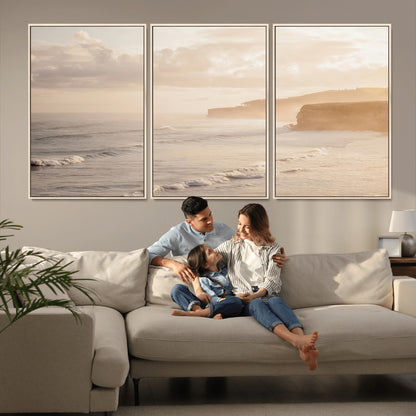 Golden hour seascape with misty cliffs and gentle waves rolling towards the shore, capturing a tranquil and warm coastal atmosphere.